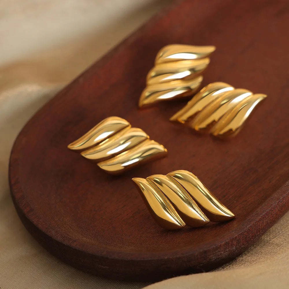 Elegant gold earrings designed with a wing motif, showcasing intricate feather details