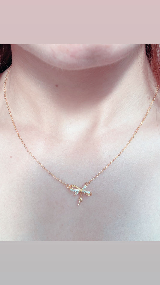 A small, gold pendant hangs at the center of the ribbon.