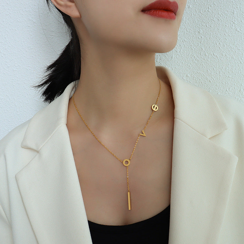 A dainty gold necklace featuring a delicate pendant engraved with “self-love.”