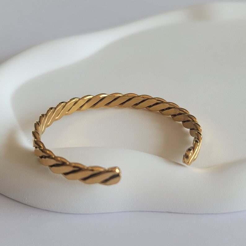 Gold braided bracelet on a white background