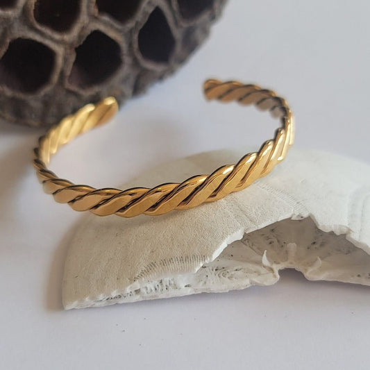 Gold braided bracelet on a textured surface