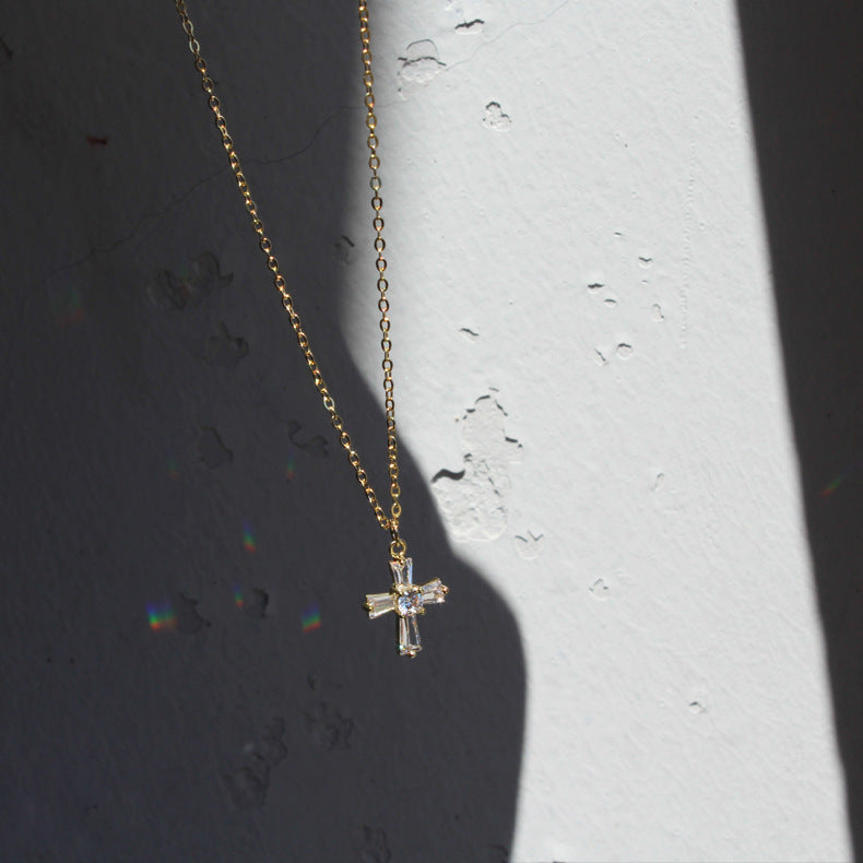 The cross is slim, polished, and reflective in the soft lighting.