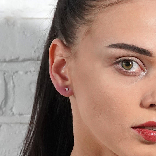 Close-up of a woman wearing a diamond earring against a light gray background