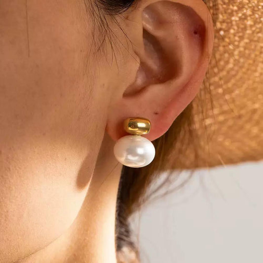 Pearl earring with gold post worn by a person