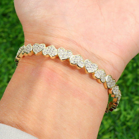 The bracelet is made from polished metal, offering a smooth and shiny finish that enhances its refined look.