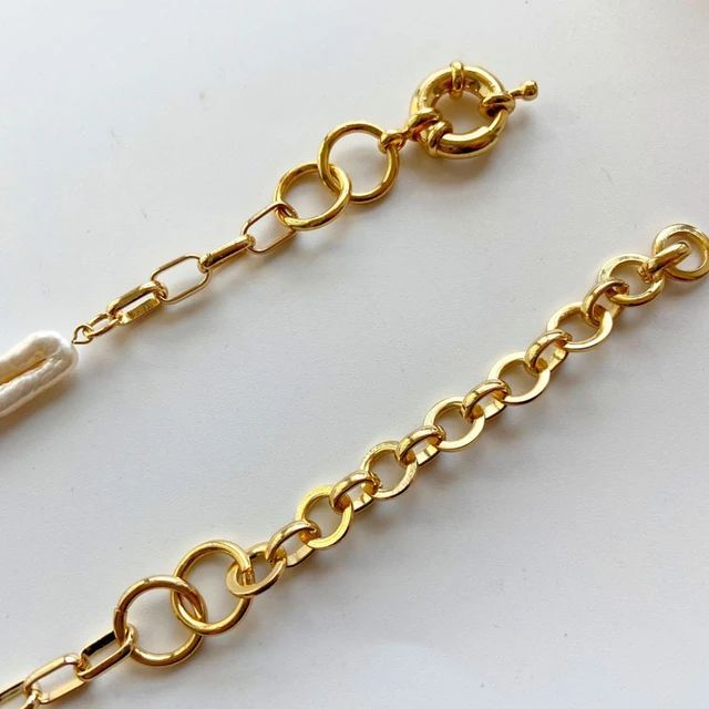 With its chunky links and irregular pearls, this necklace offers a striking contrast of textures, elevating any ensemble.