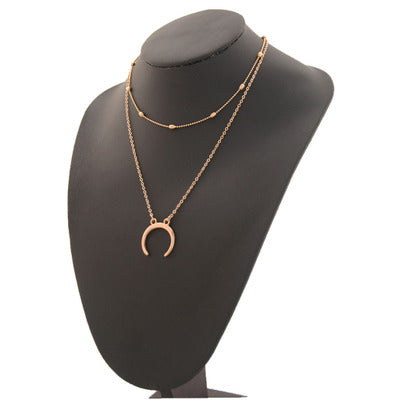 A celestial-inspired necklace featuring layered chains with half-moon pendants.